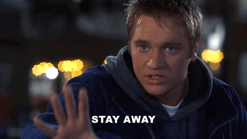 a man in a blue jacket holds up his hand in front of the word stay away
