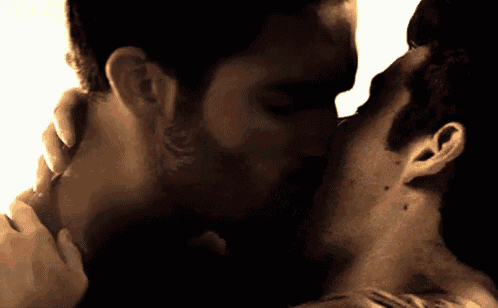 two men are kissing in a dark room