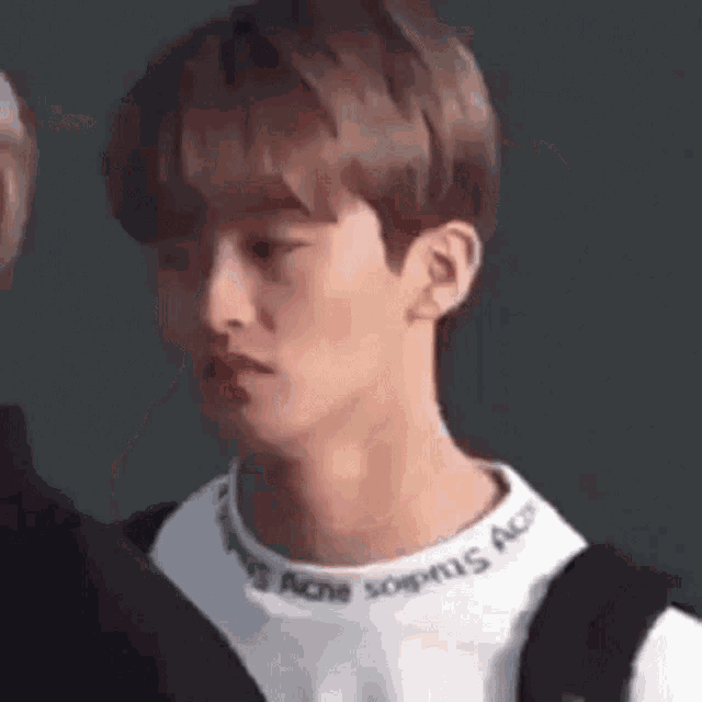 a close up of a young man wearing a white sweater and a black backpack .