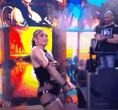 a woman in a black outfit is dancing on a stage in front of a large screen .