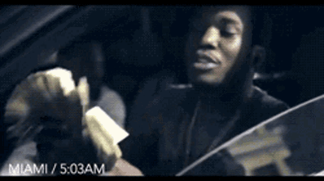 a man in a car is holding a bunch of money ..