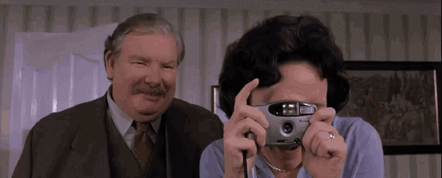 a man and a woman are taking a picture with a camera