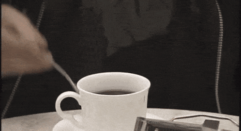 a person is drinking from a white cup with a black handle