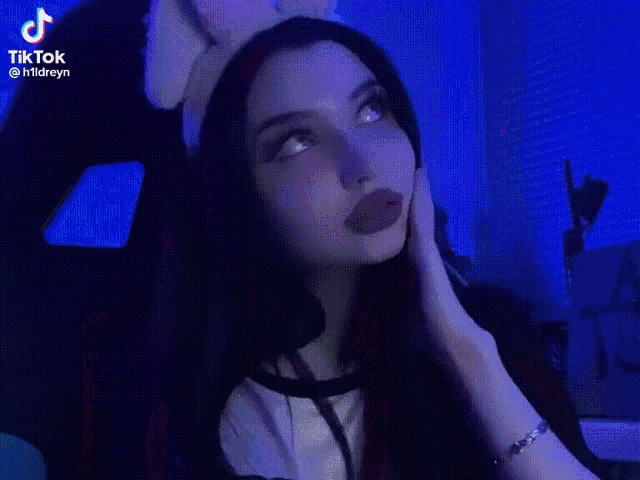 a girl with long black hair is wearing a pink headband and making a peace sign with her hands .