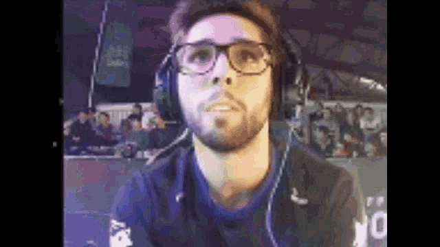 a man with glasses and a beard is wearing headphones and a microphone .