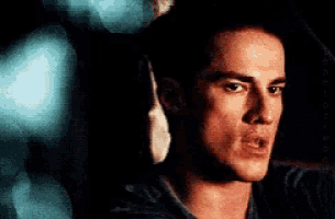 a close up of a man 's face in a dark room looking at the camera .