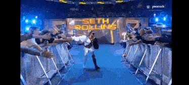 a wrestler named seth rollins is walking through a crowd of people .