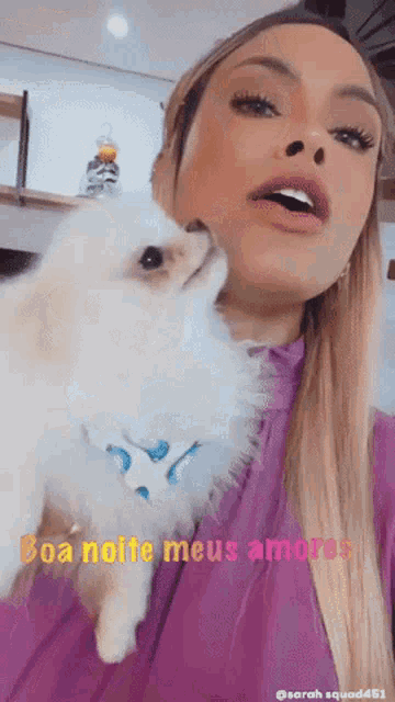 a woman holding a small white dog with the words boa noite meus amores written on the bottom
