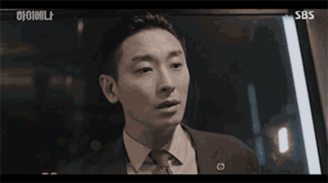 a man in a suit and tie is making a funny face in front of a sbs sign .