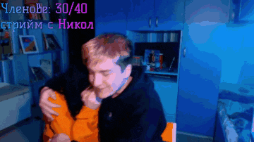 a man in a black hoodie is hugging another man in an orange hoodie in front of a sign that says 30 40