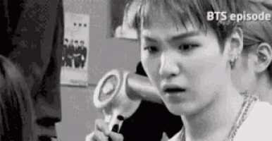 a black and white photo of a young man holding a microphone and making a funny face .