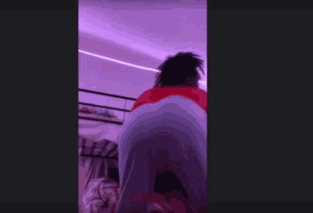 a person with dreadlocks is dancing in a room with purple lights