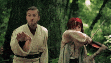 a man and a woman are playing violins in the woods