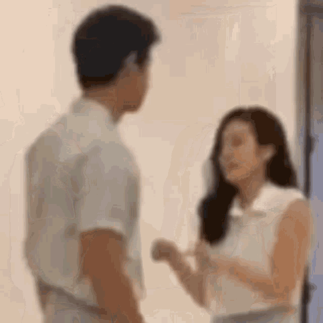 a man and a woman are standing next to each other in a room and talking to each other .