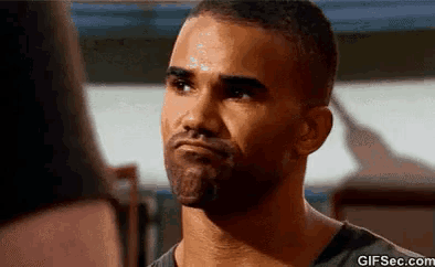 a man with a beard is looking at another man with a serious look on his face .