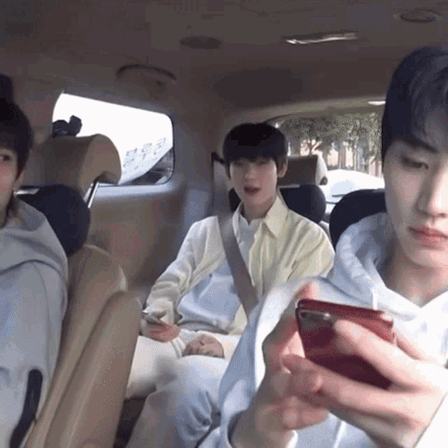 a group of young men are sitting in the back seat of a car