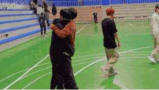 a group of people are hugging on a basketball court in a stadium .