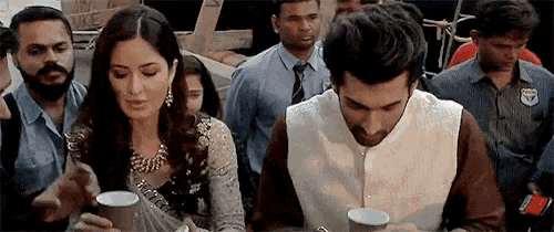 a man and a woman are sitting at a table drinking coffee from cups .