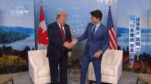 a man in a suit shakes hands with another man in front of a sign that says ' 2018 ' on it