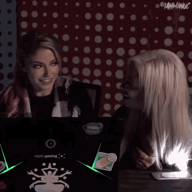 two women are sitting in front of a laptop that says elgato gaming on it