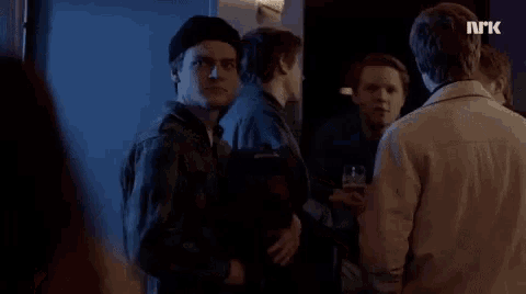 a group of young men are standing in a dark room with a sign that says nrk on it