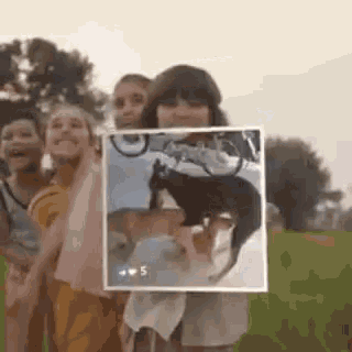 a group of children are standing in a field holding a picture of a goat .