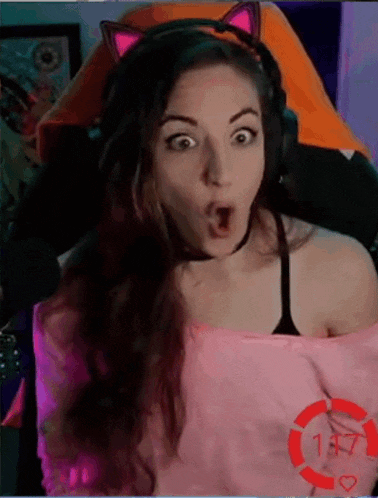 a woman wearing headphones and a cat ear headband is sitting in a gaming chair .