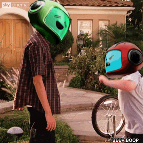 a boy wearing a green helmet stands next to a boy wearing a red helmet with the words beep boop on it