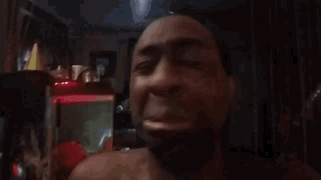 a man is crying in a dark room with a foreign language behind him