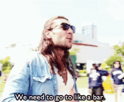 a man wearing sunglasses and a denim jacket says we need to go to like a bar