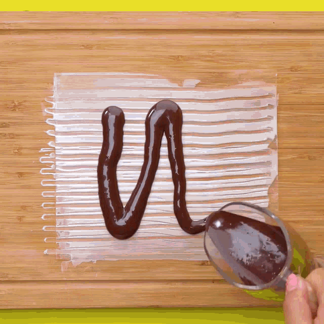 a person is pouring chocolate sauce on a piece of plastic wrap