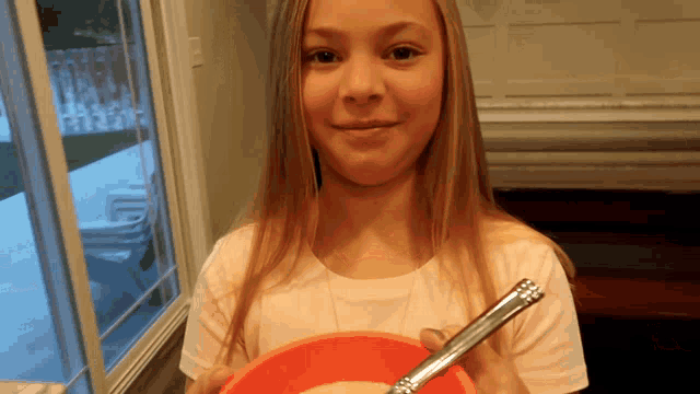 a young girl is holding a bowl and spoon