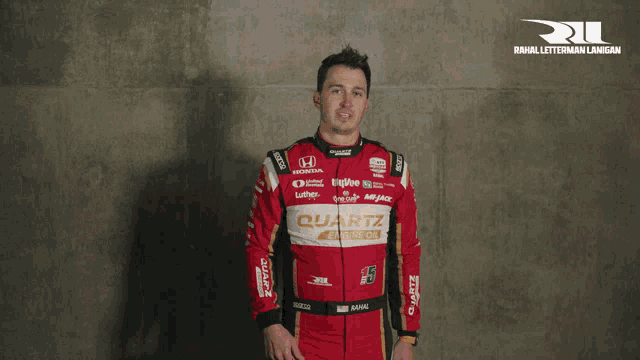 a man in a red race suit is giving a thumbs up sign