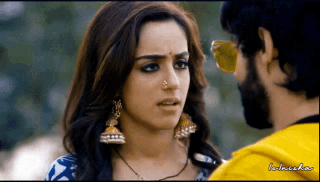 a woman with a nose ring looks at a man with sunglasses