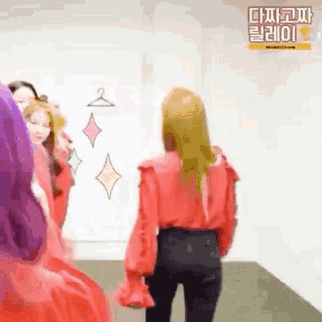 a woman in a red shirt and black pants is standing in front of a white board .