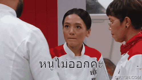 a woman wearing a white and red hk shirt stands in front of a man