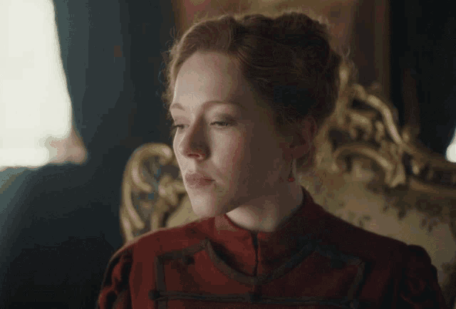 a woman in a red dress sits on a chair with her eyes closed