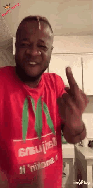 a man wearing a red shirt with the letter m on it giving the middle finger