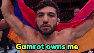 a shirtless man is holding a colorful flag with the words gamrot owns me above him