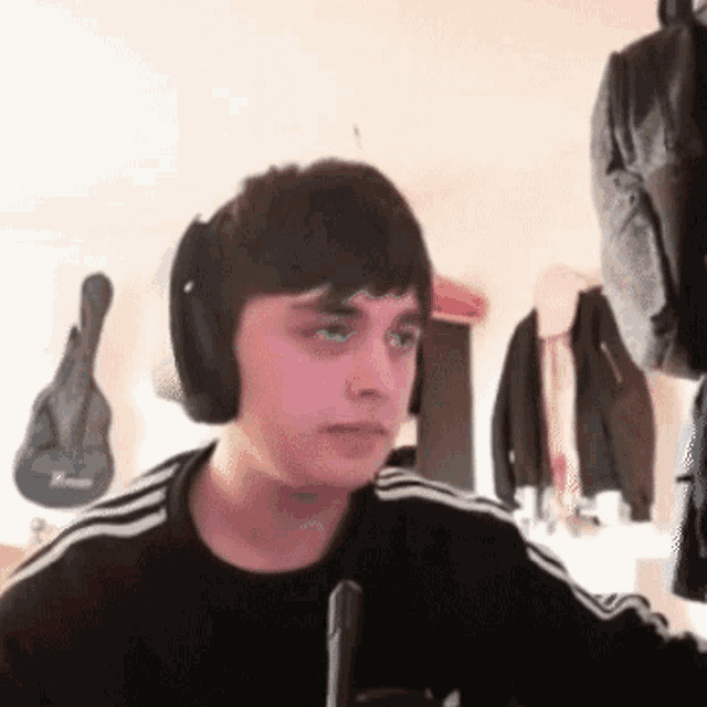a young man wearing headphones is sitting in front of a microphone in a room .