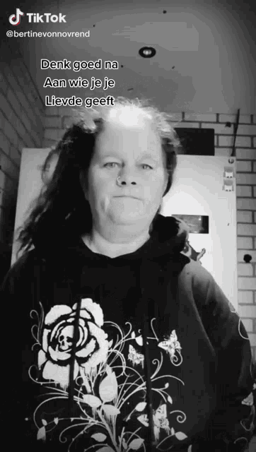 a woman is wearing a black hoodie with a rose on it and the words denk goed na aan wie je je lieve geef
