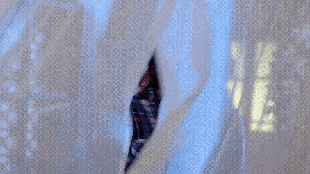 a woman wearing glasses and a plaid shirt is laughing through a window .