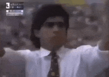 a man in a suit and tie is standing in front of a crowd with his arms in the air .