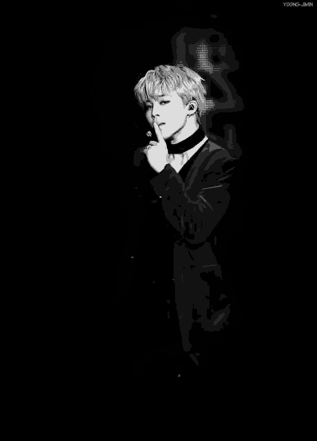 a black and white photo of a young man wearing a choker and a microphone .