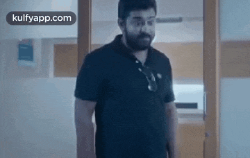 a man with a beard is standing in a room in front of a glass door .