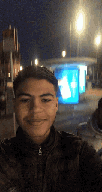 a young man taking a selfie in front of a sign that says ' ambulance ' on it