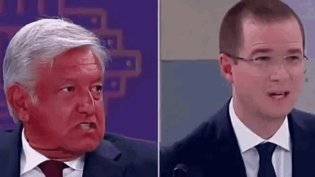 a man in a suit and tie is making a funny face next to another man in a suit .