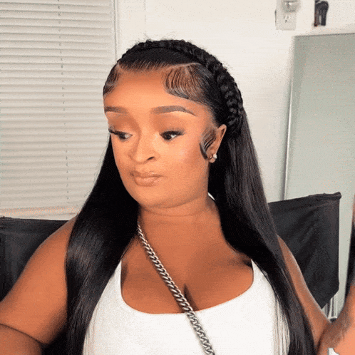 a woman wearing a braided ponytail and a white tank top