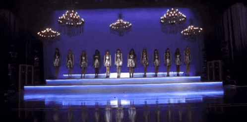 a group of women are standing on a stage with a blue backdrop