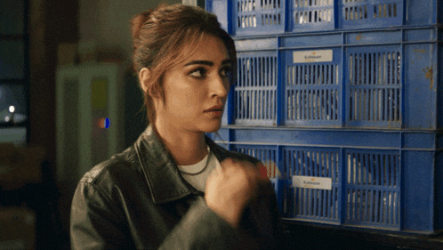 a woman in a leather jacket is standing in front of a stack of blue crates with the word johnson on them